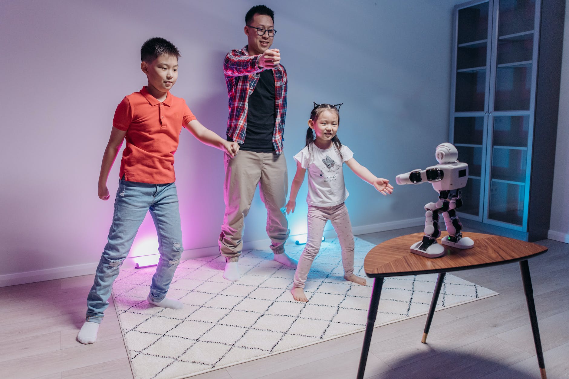 a man with his kids standing while looking at the robot on a wooden table